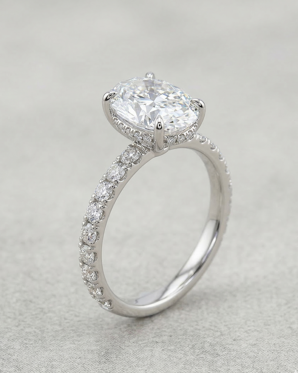 Silver ring with a large central diamond and smaller diamonds on the band against a light gray background