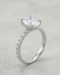 Silver ring with a large central diamond and smaller diamonds on the band against a light gray background