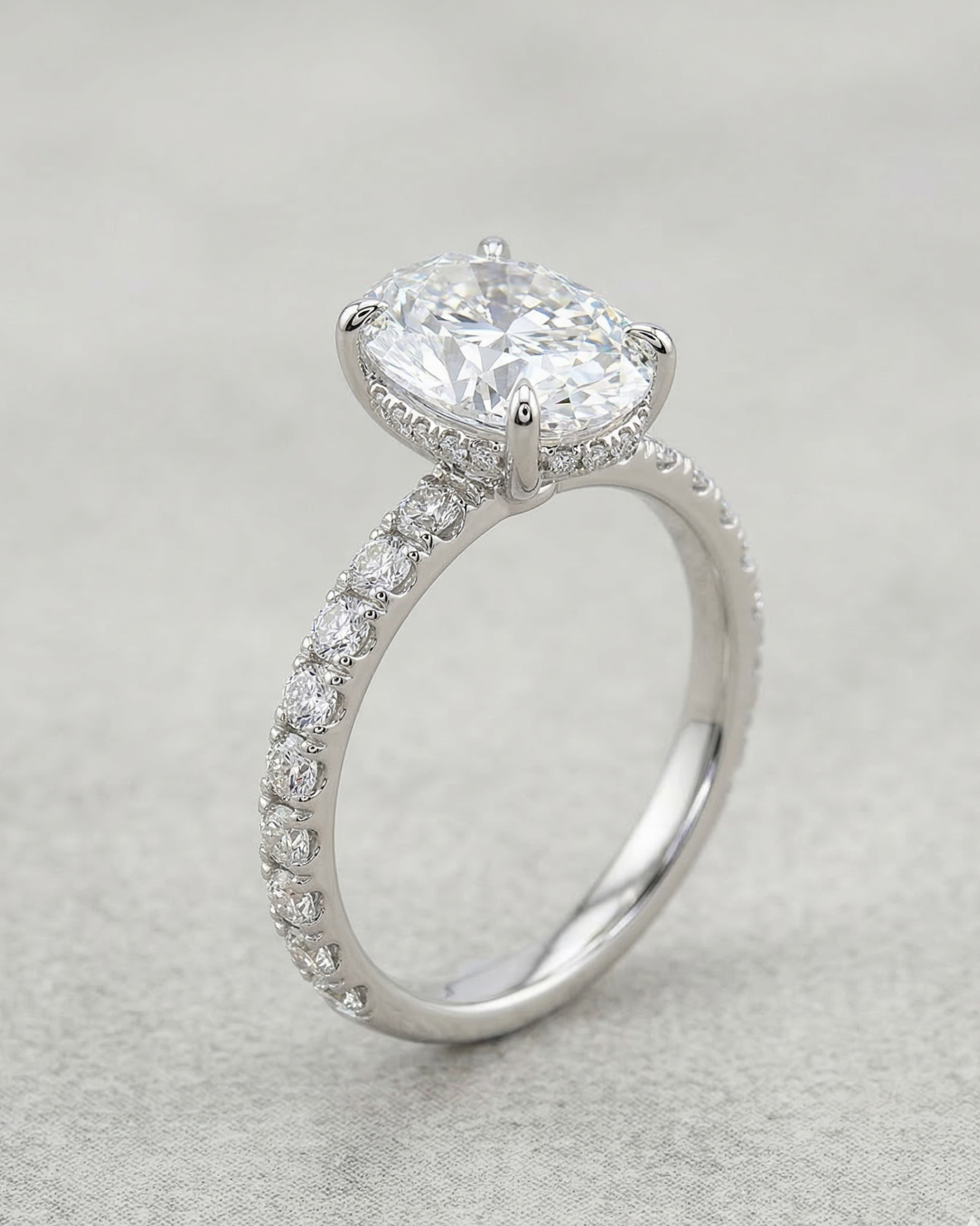 Silver ring with a large central diamond and smaller diamonds on the band against a light gray background