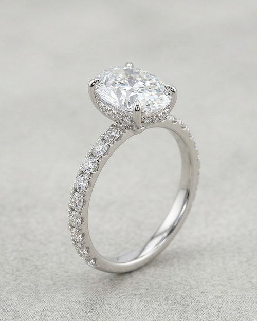 Silver ring with a large central diamond and smaller diamonds on the band against a light gray background