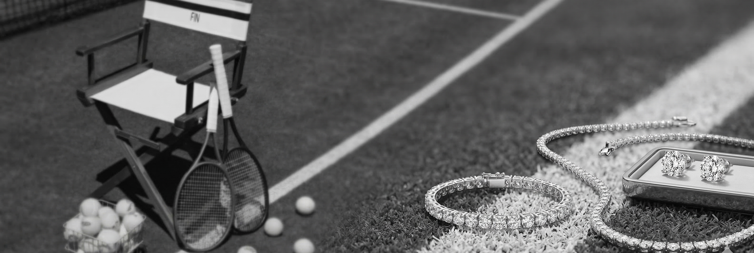 Tennis racket, balls, and director's chair on a tennis court with jewelry on the side.